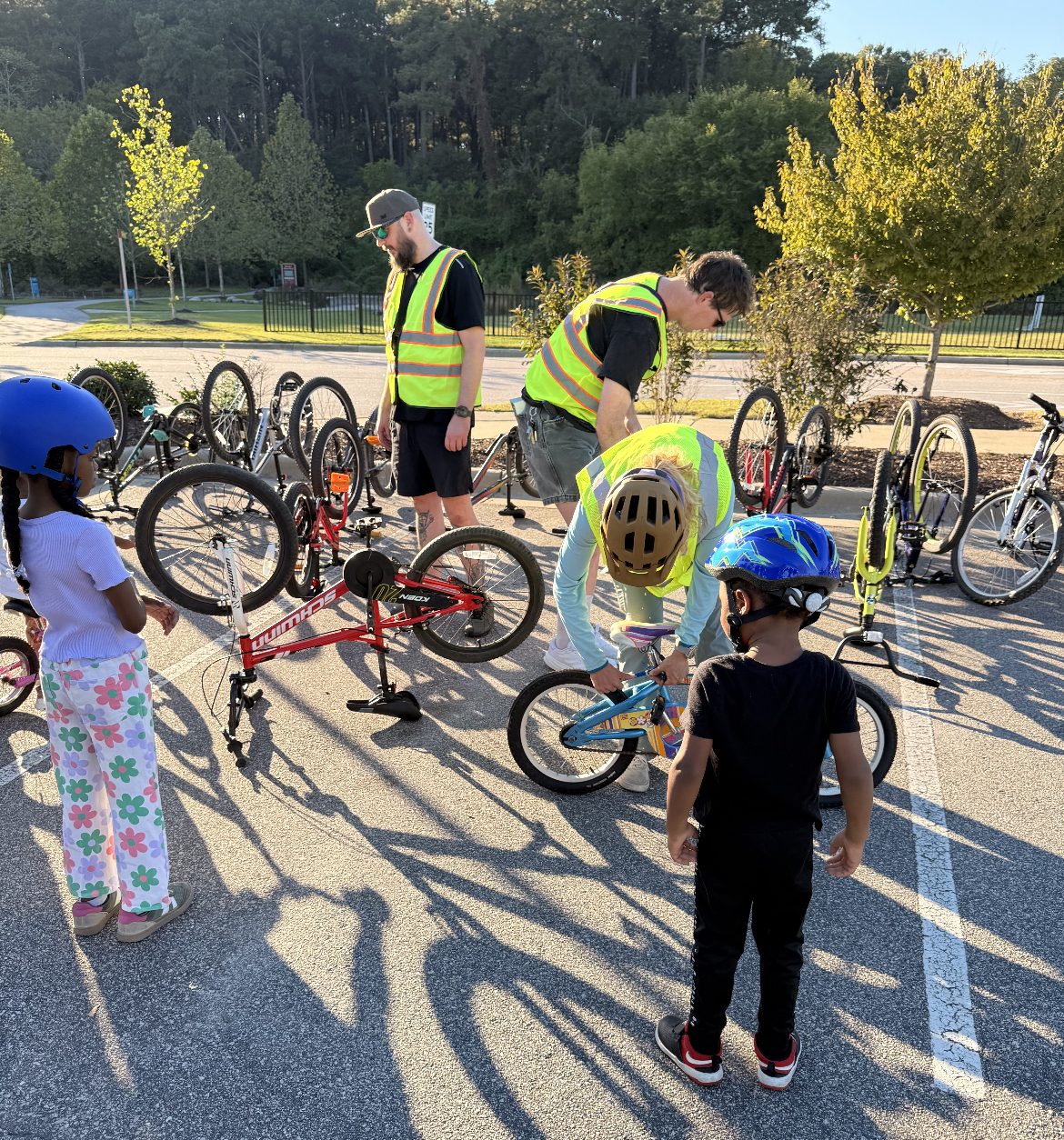 Volunteers in safety vests fit and adjust bikes for young riders