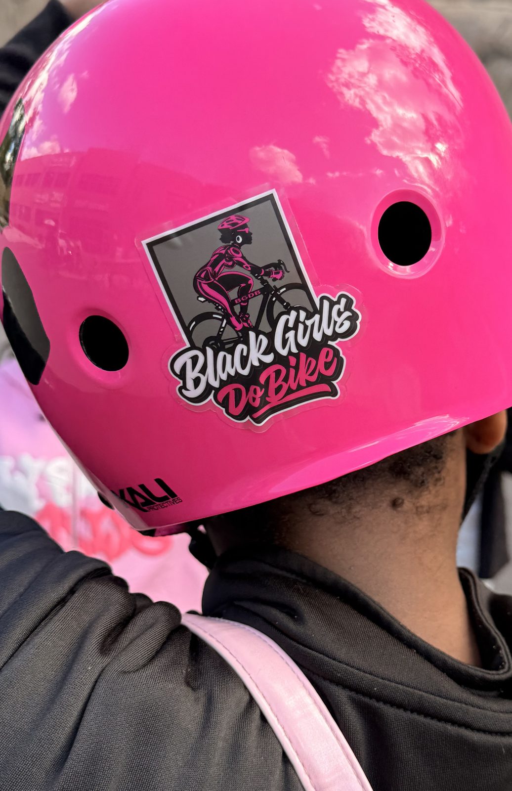 A pink helmet with a Black Girls Do Bike sticker