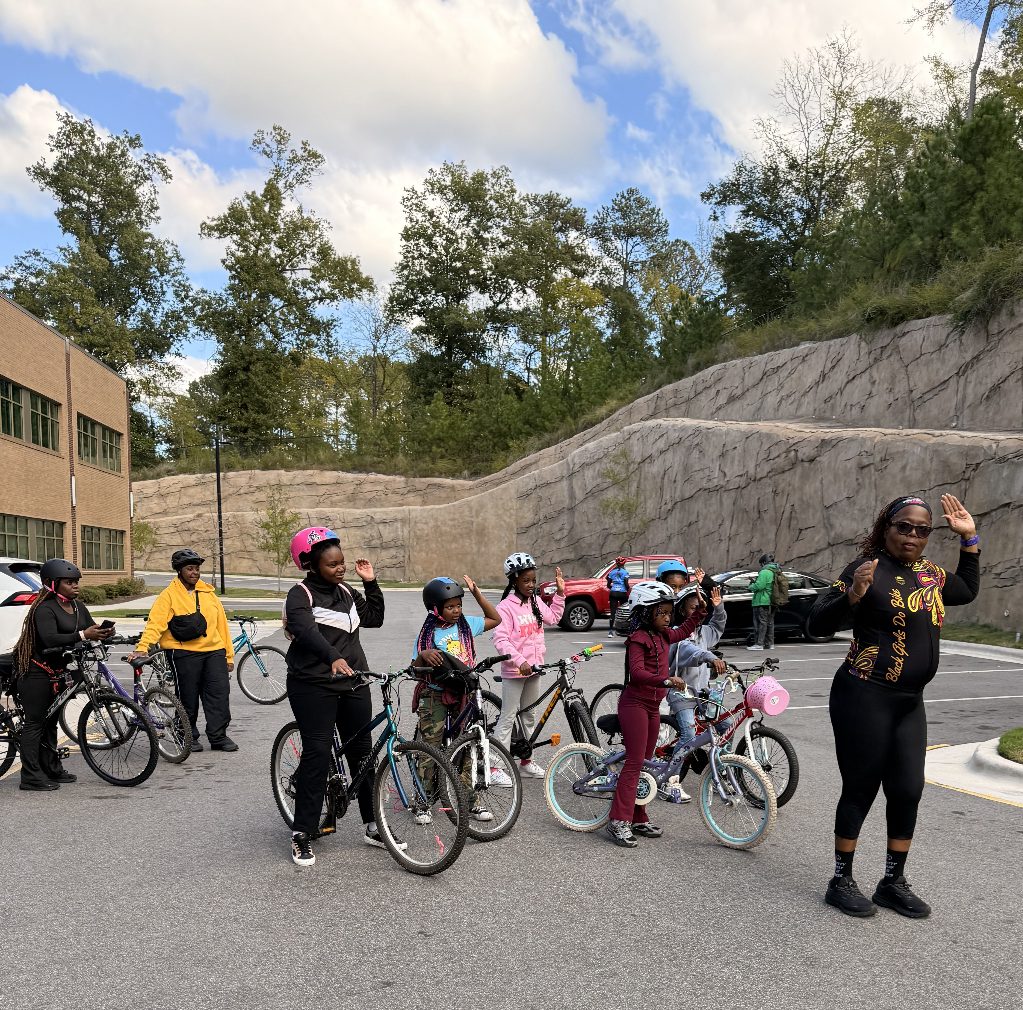 Riders wave as a Black Girls Do Bike leader gives instructions