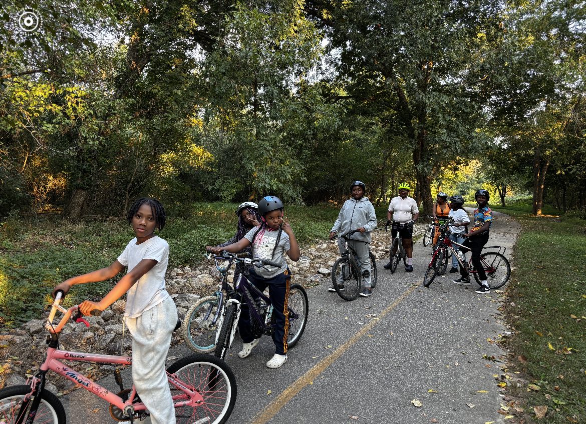 Riders pause together on a tree-lined trail