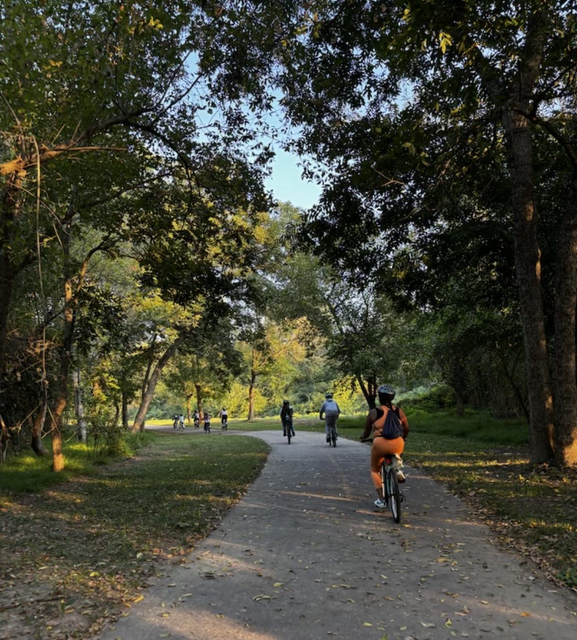 The group rides along a shaded greenway trail